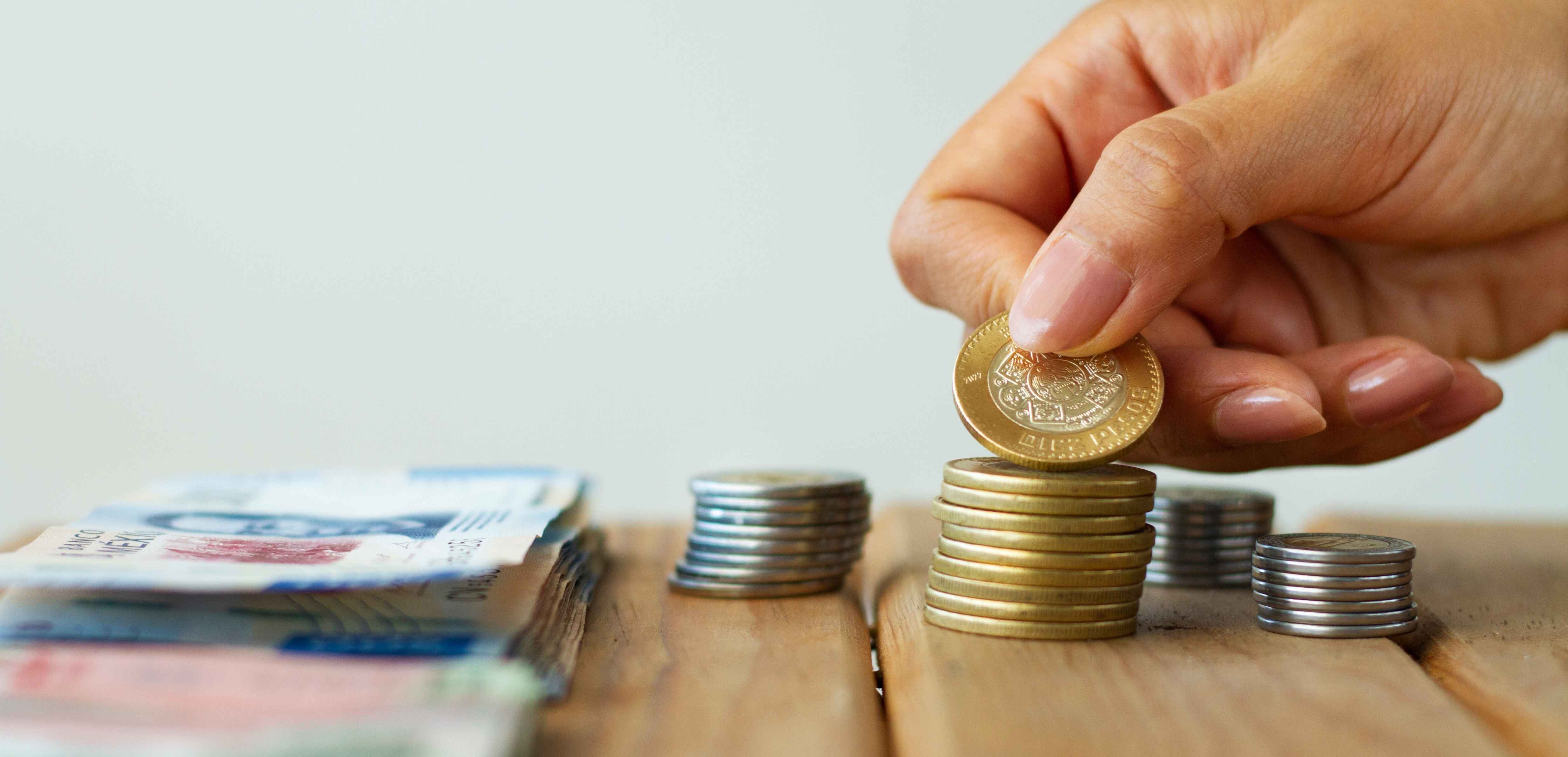 Mano contando monedas y billetes para saldar deuda con el programa de Infonavit