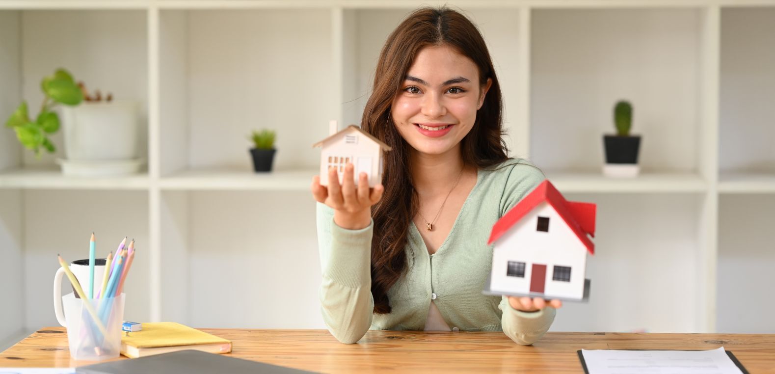 mujer joven con casas miniatura en las manos