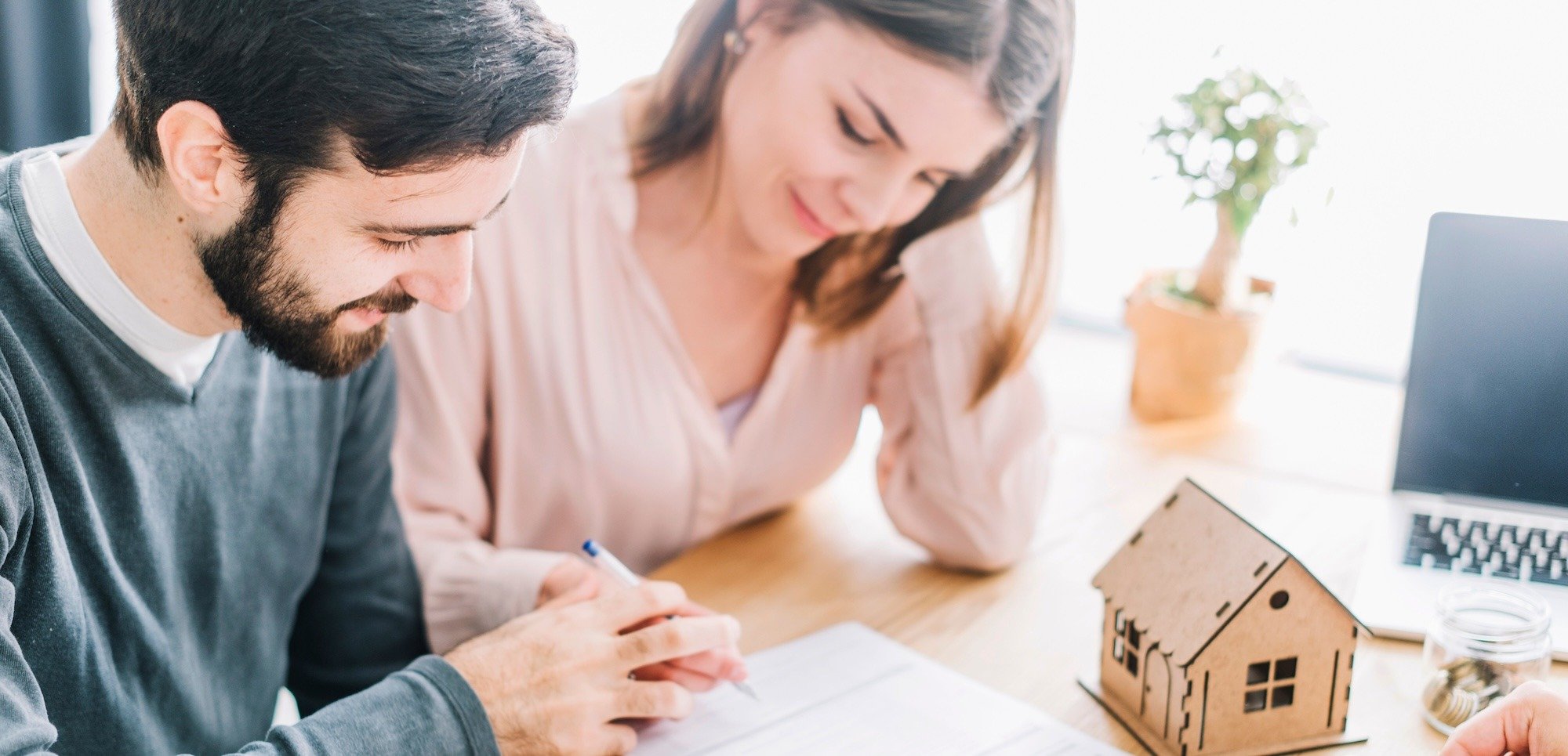 Pareja firmando acuerdo para unir sus créditos de Infonavit y Fovissste